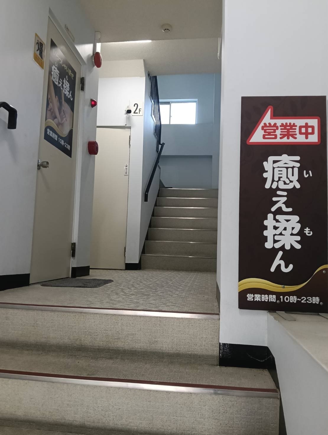 2階フロアへ続く階段と営業中の案内看板